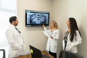 Equipo de dentistas y asistentes en el consultorio revisando una radiografía - Dentist Salud Matthews Charlotte North Caroline